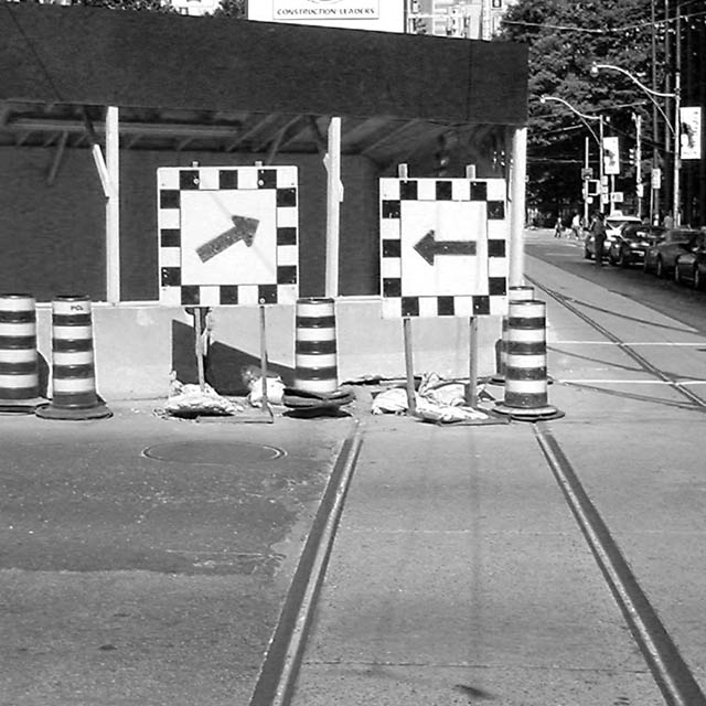 black and white, photograph, toronto, constuction signs, conflict, arrows